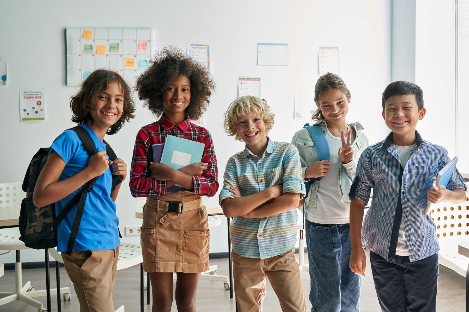 Five students in a classroom smiling at the camera.