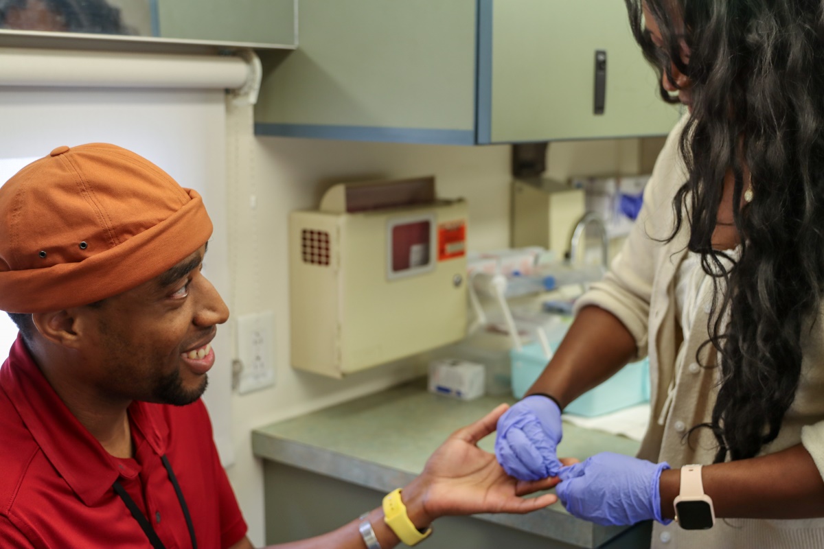 A Mobile Health Unit staff member helps a client with a health screening.